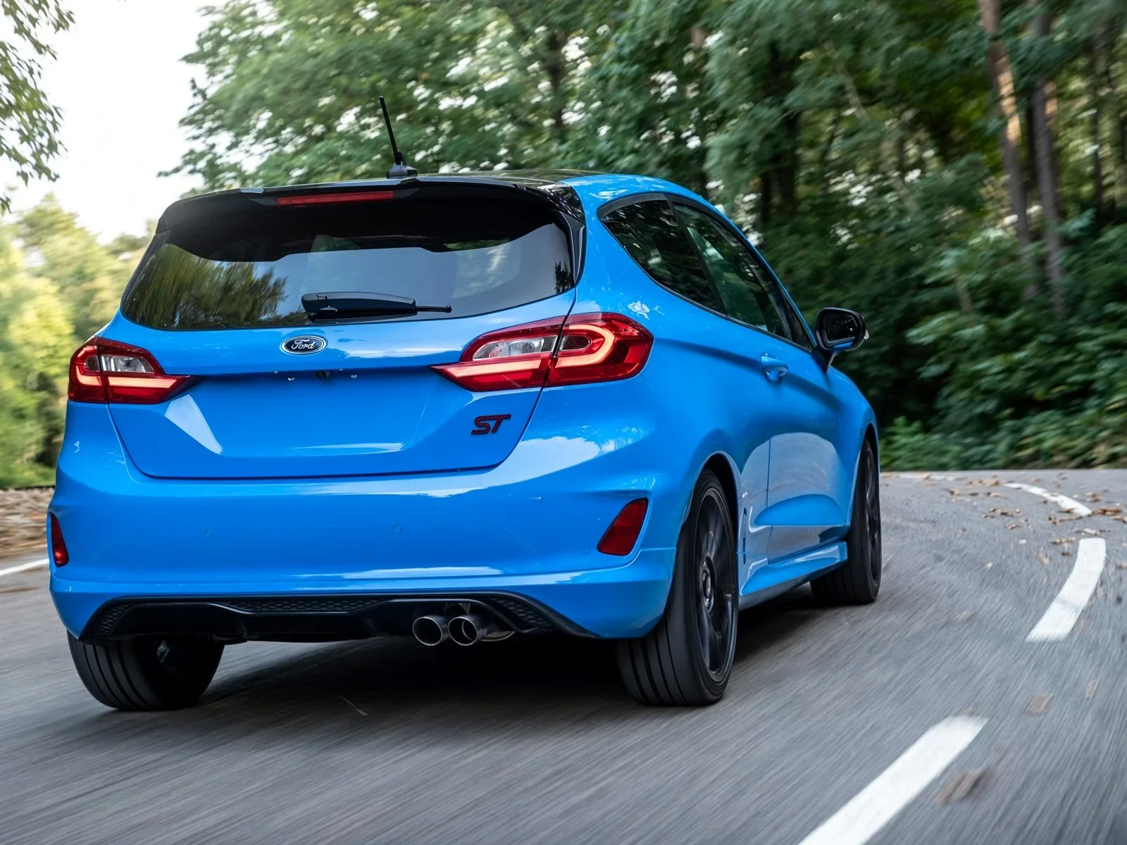 Parte trasera de un Ford Fiesta ST azul en movimiento con escape doble