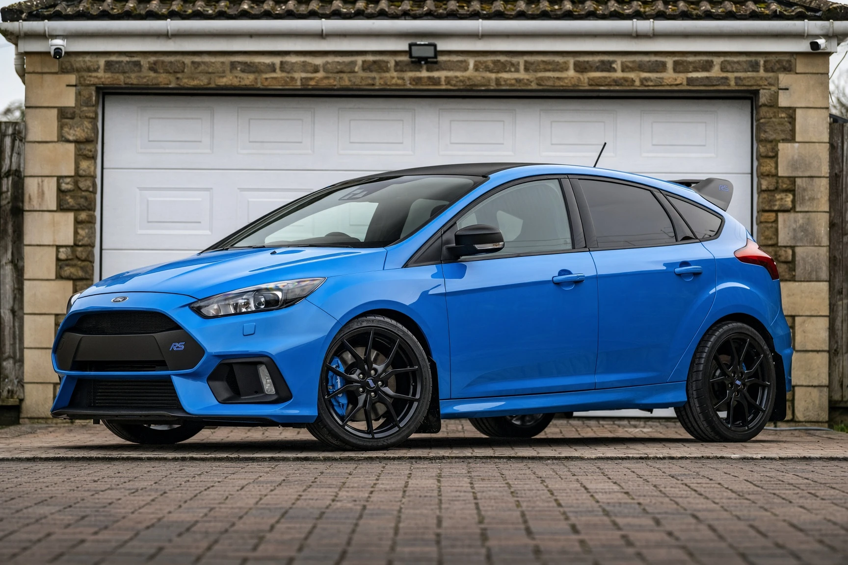 Ford Focus RS Mk3 azul en tres cuartos lateral, aparcado frente a un garaje