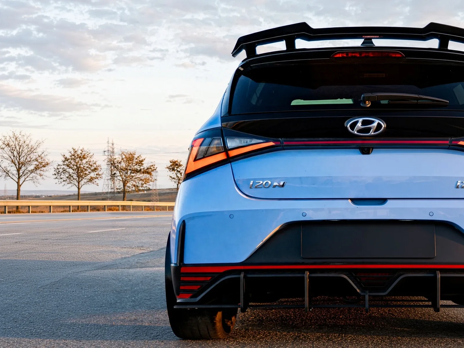 Parte trasera de un Hyundai i20 N azul con alerón y difusor al atardecer