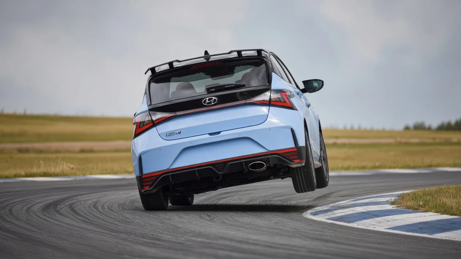 Hyundai i20 N azul visto desde atrás en circuito con una rueda levantada